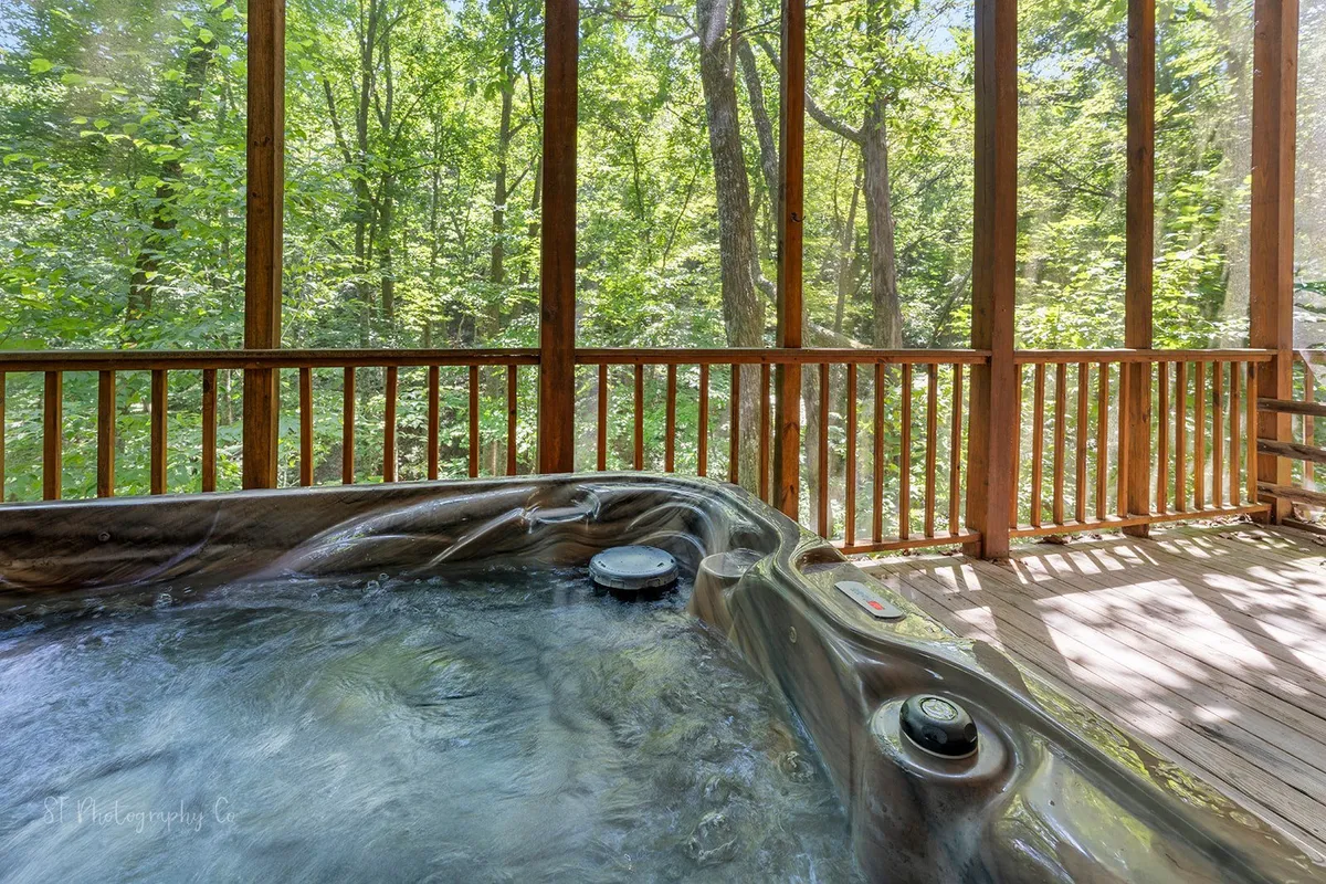 This interior scene showcases a hot tub on a private porch or deck, enveloped by lush greenery. The space is designed for unwinding with scenic views, offering an inviting spot for families to relax together after a day of exploration.