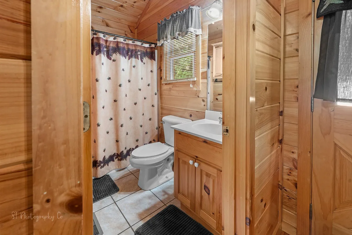 A bathroom with inviting wooden walls, a vanity sink, and a shower curtain, creating a soothing and private atmosphere. The space is well-lit and designed for relaxation and personal care after a day outdoors.