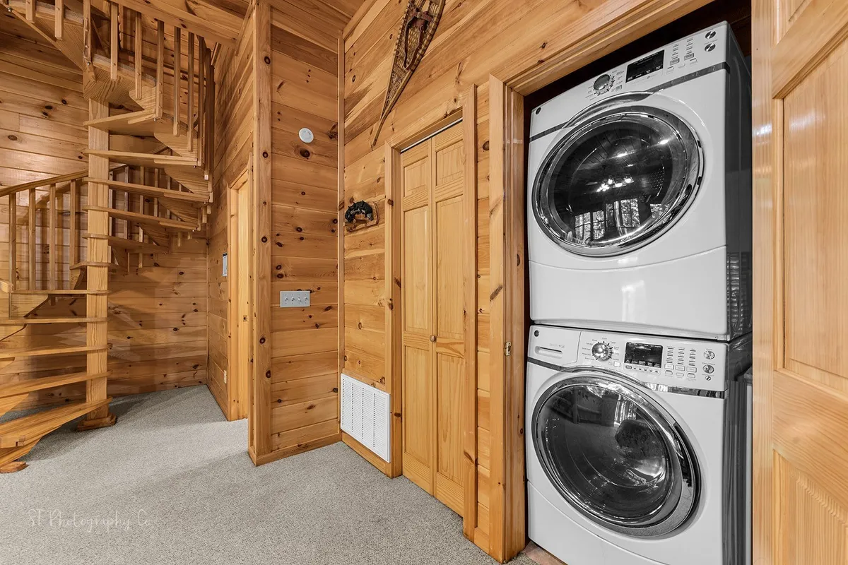 This image captures a warm, inviting entryway featuring a distinctive spiral staircase and a washer and dryer unit, all framed by rustic wooden paneling. The space signals the beginning of a seamless, homey resort experience, setting the tone for the guest's arrival and first impression.