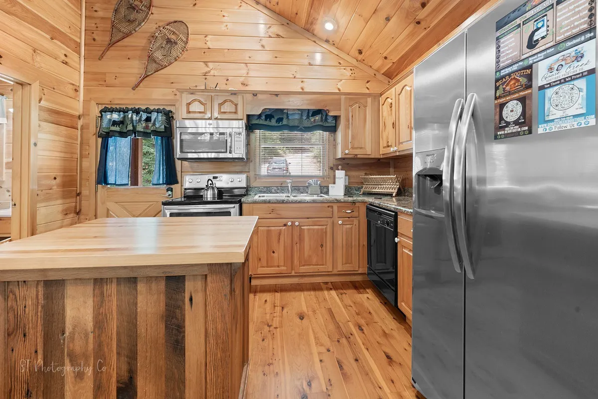 A cozy kitchen with a large island, stainless steel appliances, wooden cabinetry, and expansive windows that bathe the space in natural light. The area is set up for cooking, casual dining, and family gatherings, highlighting opportunities for guests to create and share meals.